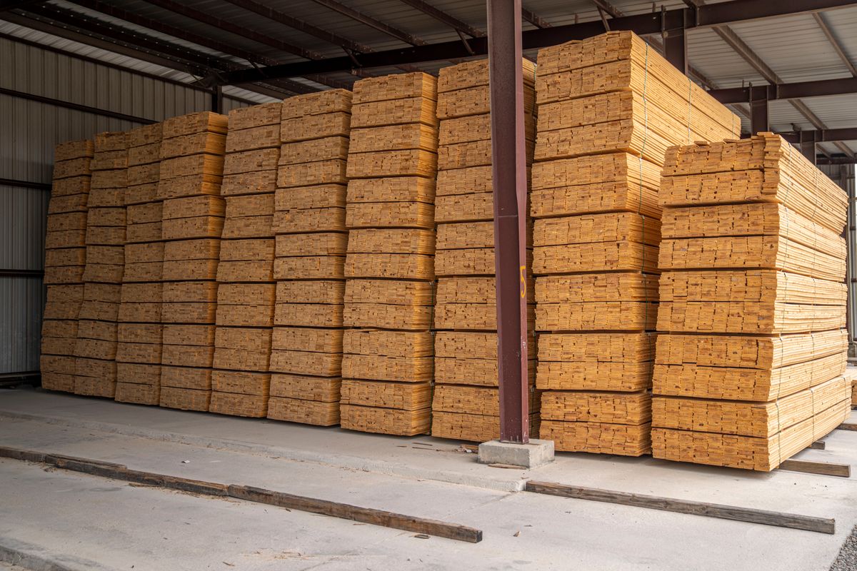 Orderly stacks of sawn hardwood lumber inside a covered warehouse
